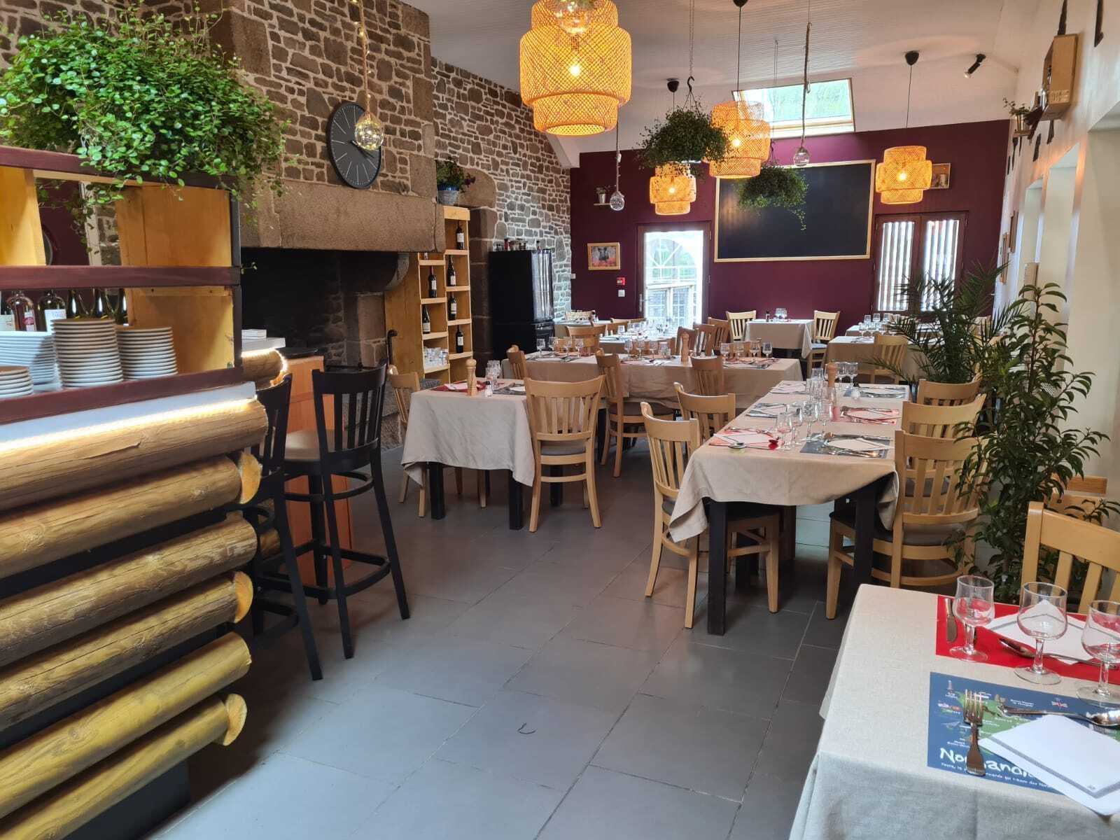 A restaurant with wooden tables and chairs, a brick wall, and hanging lights.