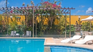 A swimming pool with lounge chairs and a pergola with flowers. - Casa com Piscina no Iguape 50m do Mar (Aquiraz)