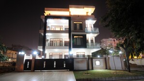 A multi-story residential building with a gated entrance, a well-maintained lawn, and a staircase leading to the upper floors. - Geetanjali Luxury Suites (Jaipur)