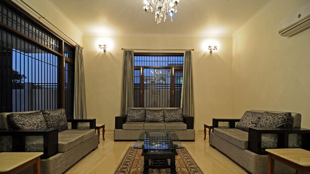 A living room with two sofas, a glass coffee table, and a patterned rug. - Geetanjali Luxury Suites (Jaipur)