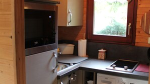 Een functionele keuken met een magnetron, oven, spoelbak en wasmachine.
