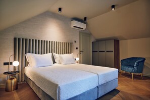 Quarto moderno com cama grande, abajures, guarda-roupa e ar condicionado.