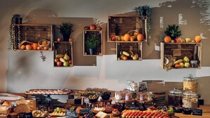 Ein reichhaltiges Buffet mit verschiedenen Speisen und eine Holzwand mit hängenden Pflanzkästen.