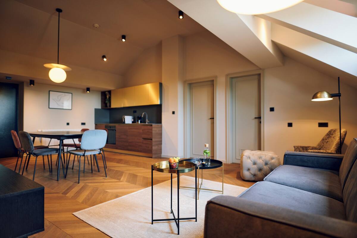 A modern living room with a sofa, a dining table with chairs, and a kitchen in the background.