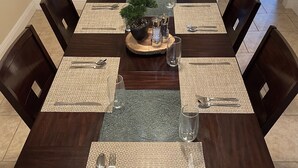A dining table set with placemats, silverware, and a centerpiece. - Mi Casa Es Su Casa!!🏡 4 Bdrm home with pool (Orlando)