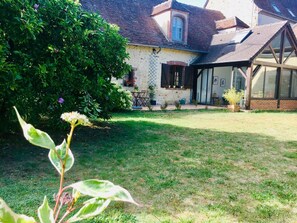 Una casa con jardín, patio y salón de cristal.
