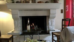 A cozy room with a fireplace, a table with a bottle and glass, and two chairs. - Take a break "Au fil de l'ô (Moutiers-au-Perche)