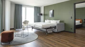A modern hotel room with a bed, a sofa, a round rug, and a chair.