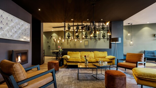 Un salon moderne comprenant un canapé, des fauteuils, une table basse et une cheminée.