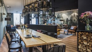 Un espace repas moderne avec une table en bois, des chaises noires et un ordinateur portable posé sur la table.
