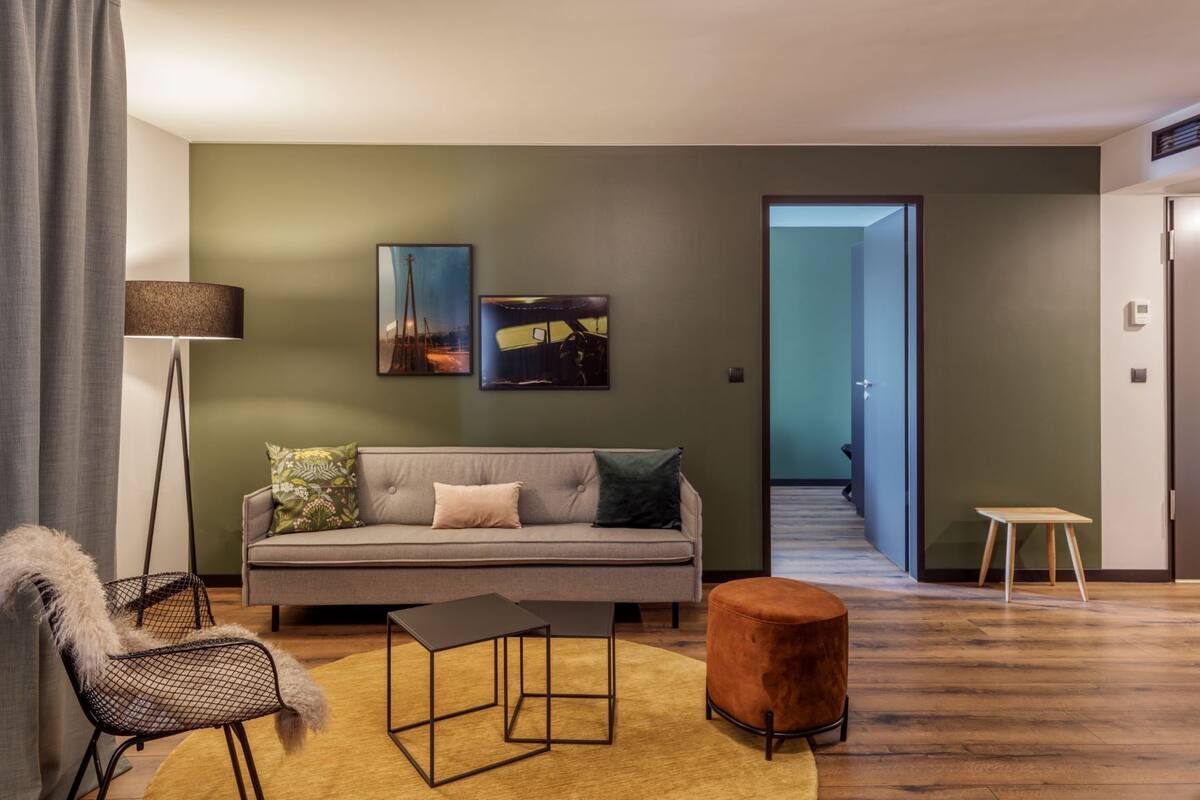 A modern living room with a sofa, a coffee table, and a floor lamp. There is a hallway leading to another room.