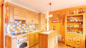 A kitchen with wooden cabinets, a tiled backsplash, and a small island.