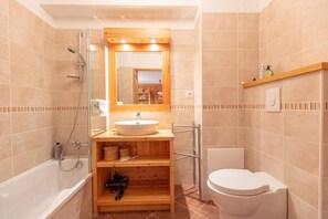 Een bad/douchecombinatie, handdoeken, zeep, toiletpapier