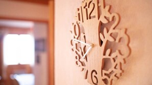 A wooden wall clock with intricate cut-out designs.