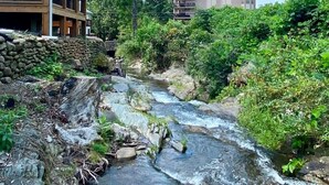 A building with a stone retaining wall and a small stream flowing through a landscaped area. - Rushing Water/Hot Tub/Walk 2 Downtown Gatlinburg (Gatlinburg)