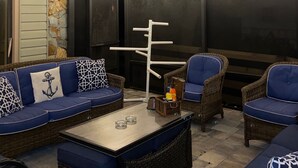 Een gezellig buitenzitje met rieten meubels en blauwe kussens, een tafel met glazen en een decoratieve muur.