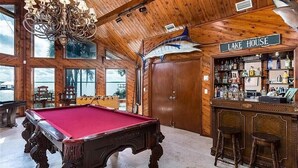 Een pooltafel in een ruimte met houten wanden en een bar, voorzien van de tekst 'LAKE HOUSE'.