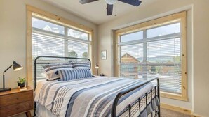Ein Schlafzimmer mit Bett, Nachttisch, Lampe und Fenstern.
