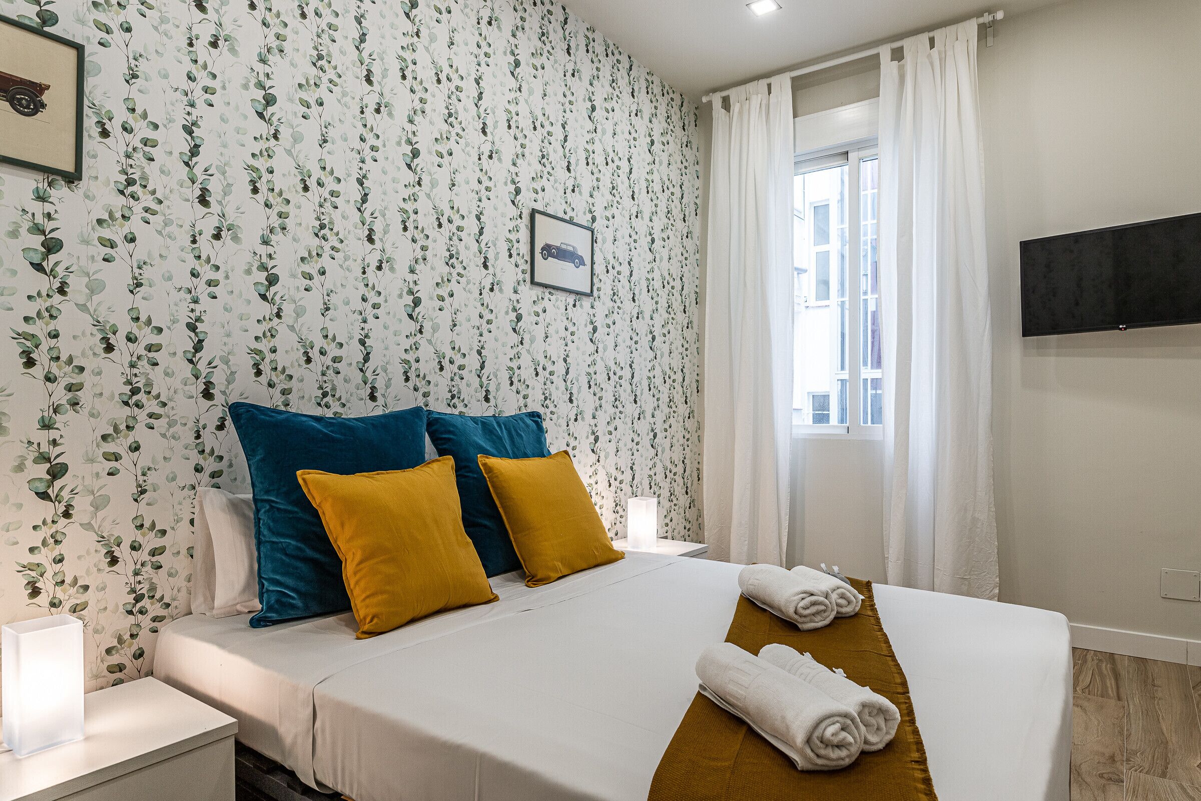 Une chambre d’hôtel avec un lit, des oreillers, une table de chevet, une lampe et une fenêtre avec des rideaux.