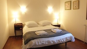 A neatly made bed with white linens and a gray blanket, two bedside lamps, and two framed certificates on the wall. - Collioure Town with Parking – Apartment Sorra (Collioure)