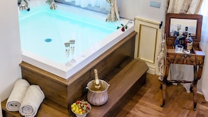 Une salle de bain luxueuse avec une grande baignoire, un meuble-lavabo en bois et un lustre.