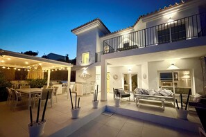 A two-story house with a balcony, outdoor seating area, and a dining table.