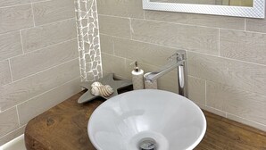 A bathroom with a white ceramic sink, a wooden vanity, a star-shaped soap dish, and a mirror with a quilted frame. - Appartamento Ibiscus (Cannigione)