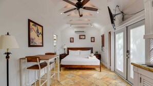 Une chambre à coucher comprenant un lit, un bureau, une chaise, un ventilateur de plafond et une fenêtre avec des stores.
