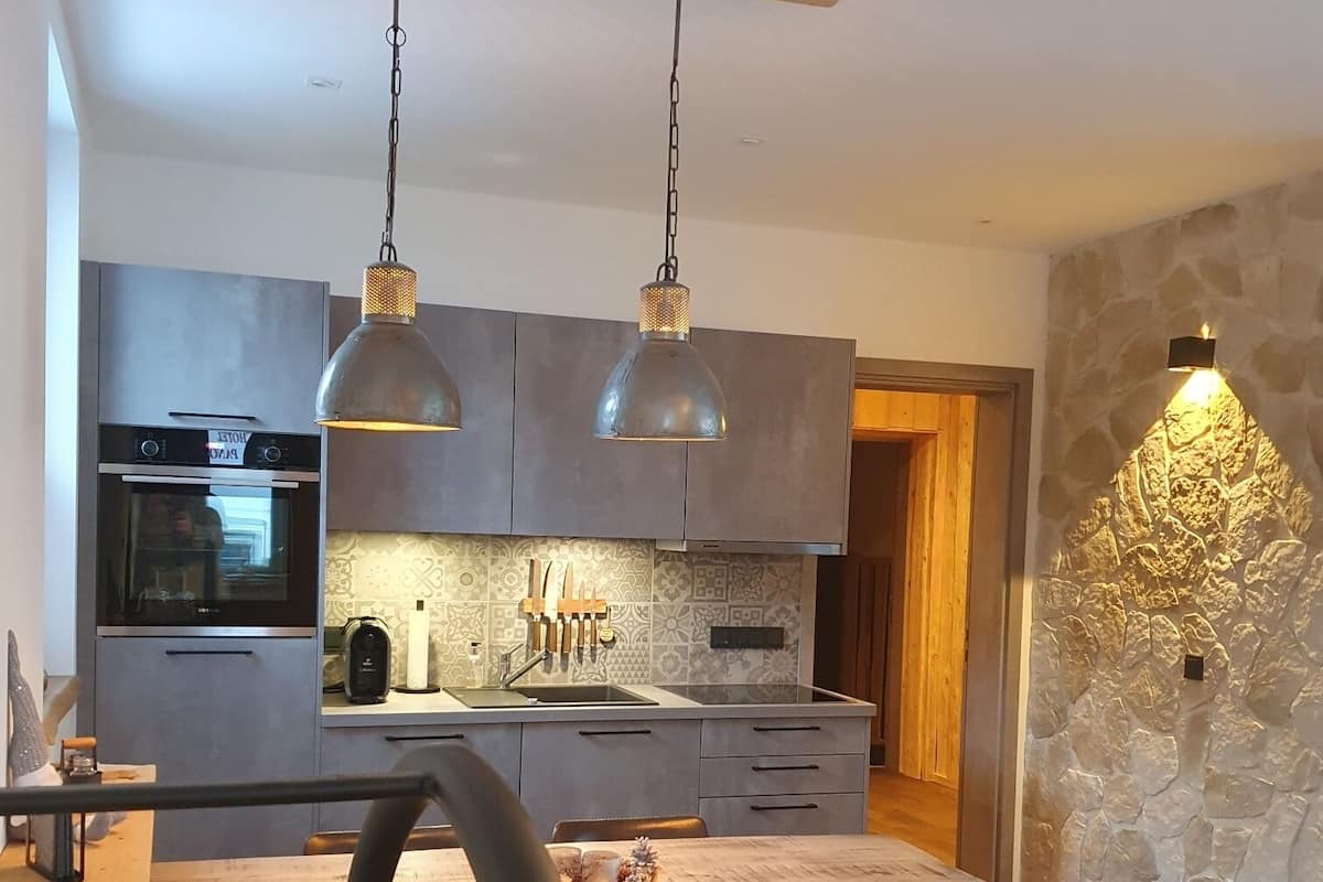 A modern kitchen with a central island, pendant lights, and a stone accent wall.