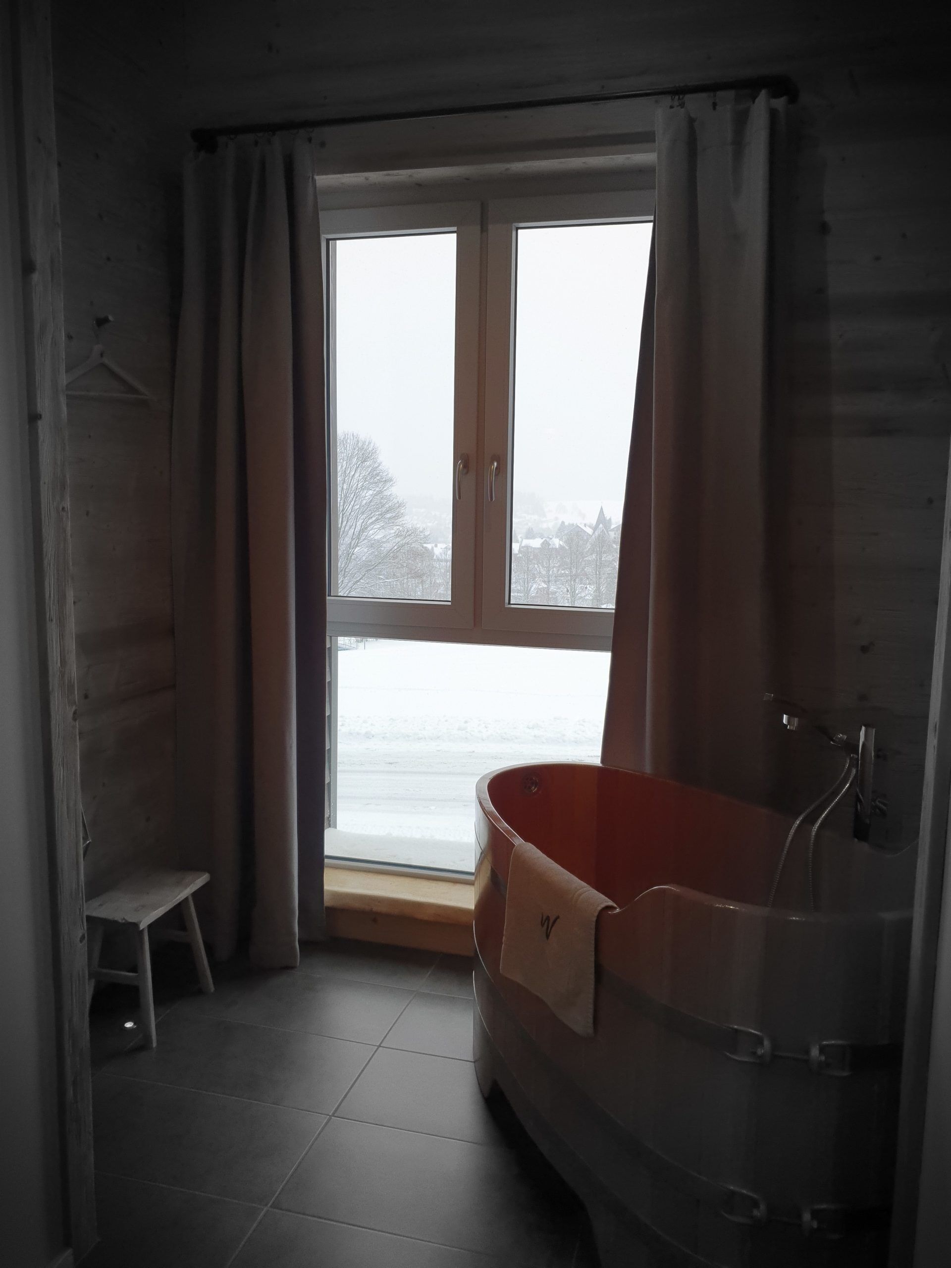 A bathroom with a bathtub, a window, and a view of a snowy landscape.