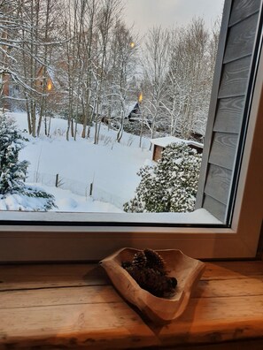 A window view of a snowy landscape with bare trees and a wooden cabin. - WLodgeOne (Braunlage)