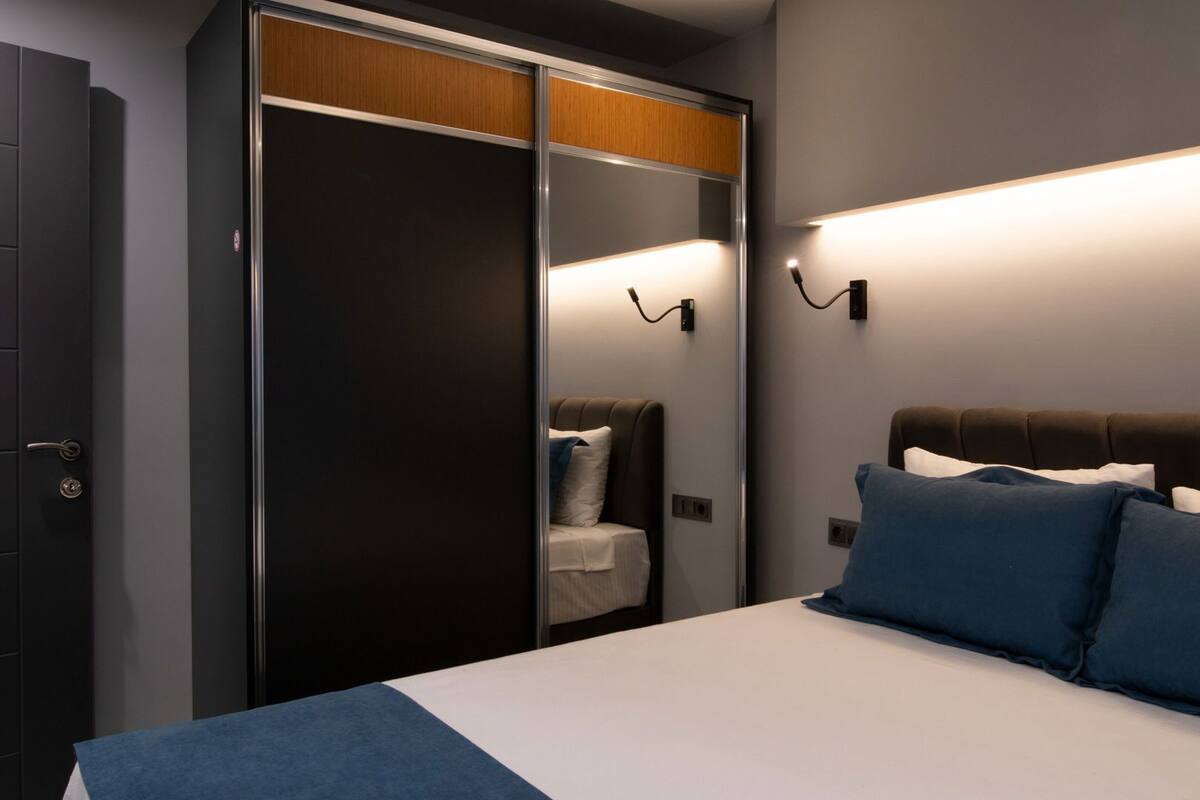 Un dormitorio con cama, lámparas de noche, armario y espejo.