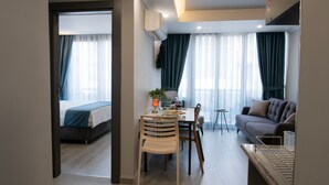 Une chambre d’hôtel moderne comprenant un lit, un coin repas avec une table et des chaises, un canapé et une petite table d’appoint.