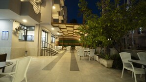Un espace café en plein air avec des tables et des chaises, un escalier et un mur végétal.
