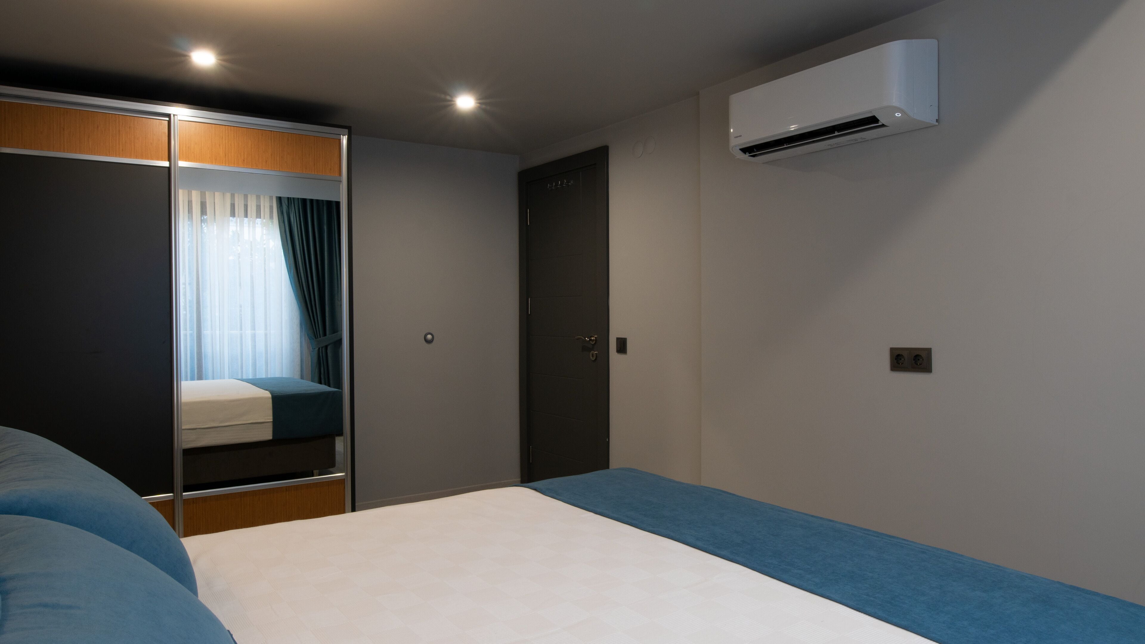 A bedroom with a bed, a wardrobe, a door, and an air conditioning unit.