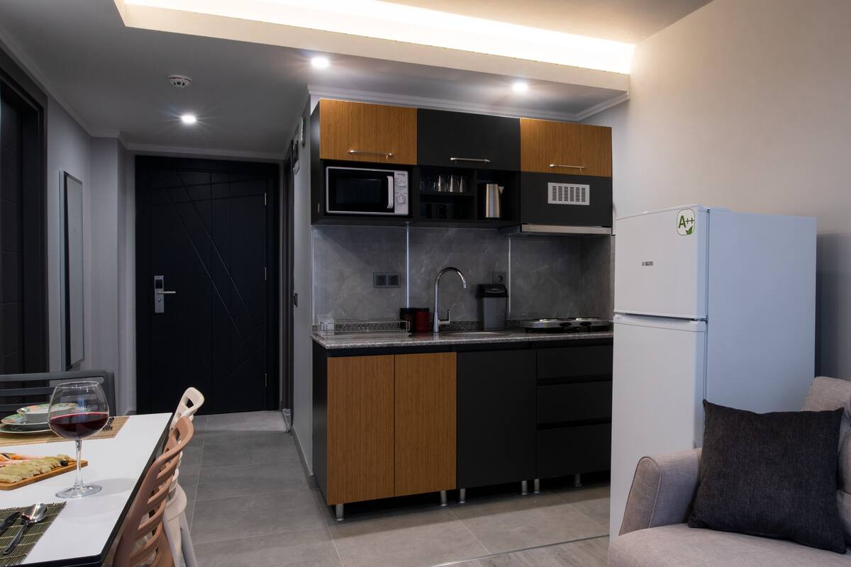 Cocina compacta equipada con microondas, estufa y refrigerador.