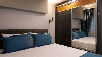 Ein modernes Hotelzimmer mit einem großen Bett, einem Schrank mit Spiegel und einem Nachttisch.