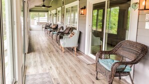 Eine überdachte Veranda mit Korbstühlen, Deckenventilatoren und Blick ins Freie.