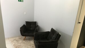 Two black armchairs with wooden legs on a white shag rug, against a plain wall with a door and an emergency exit sign. - Smart Hotel Rio Verde (Rio Verde)