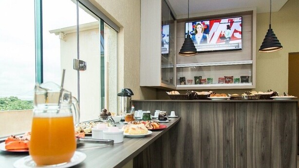 A breakfast bar with a variety of food items and a glass of orange juice. - Smart Hotel Rio Verde (Rio Verde)