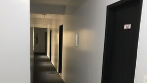 A corridor with a black door on the right, a fire extinguisher on the left wall, and a number sign on the door. - Smart Hotel Rio Verde (Rio Verde)