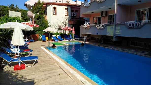 Una piscina con acqua azzurra, circondata da lettini e ombrelloni.