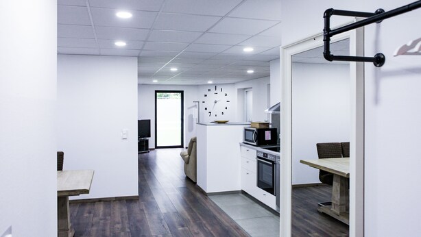Una cocina moderna con armarios blancos, un microondas y un reloj en la pared.