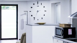 Una cocina moderna con un reloj empotrado, microondas, horno y una mesa de comedor de madera.