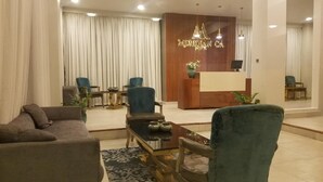 A hotel lobby with a reception desk, seating area, and a large mirror reflecting the space. - Meridian C.A (Dar es Salaam)