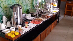 A buffet setup with various food items and beverages, including coffee machines, a fruit tray, and condiments. - Meridian C.A (Dar es Salaam)