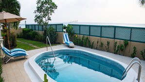 Une piscine avec deux chaises longues et un parasol.