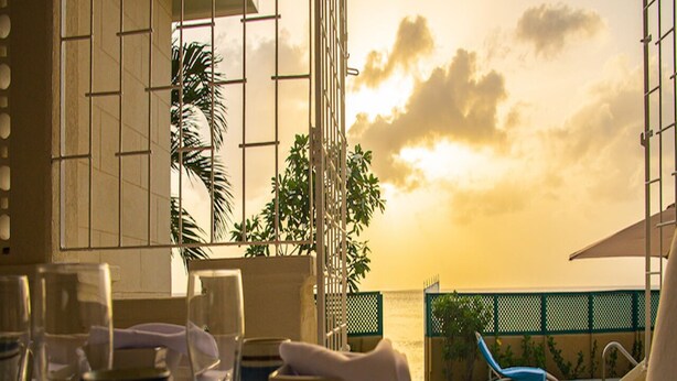 Une table dressée pour deux personnes, avec vue sur la mer et le coucher de soleil.