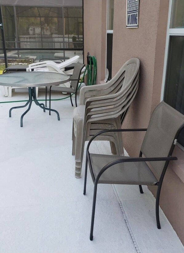 Relax in this outdoor seating area with comfortable chairs and a table, surrounded by a glass wall and a window.