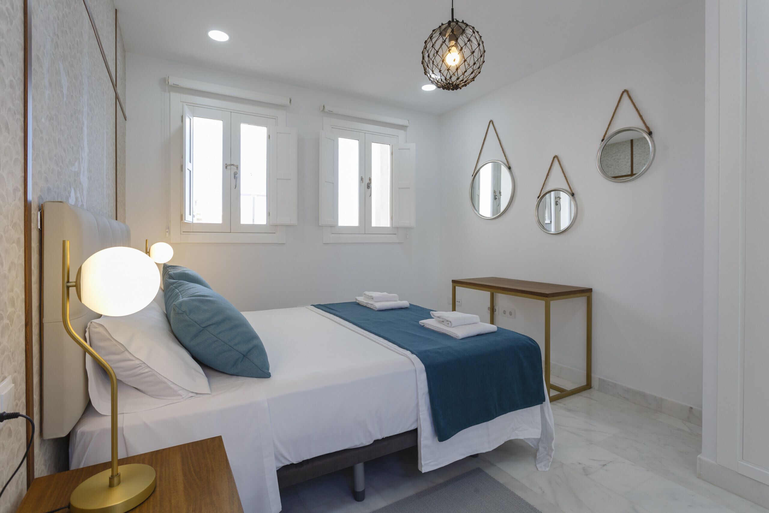 A neatly arranged bedroom with a bed, bedside lamp, and a bedside table.